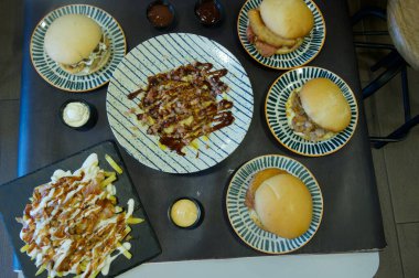 İçinde sandviç, patates kızartması ve diğer yemek çeşitleri olan bir masa. Masa yemek ya da toplanma için hazır.