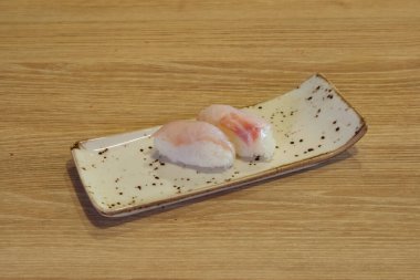 Üzerinde bir parça balık olan beyaz bir tabak. Balık ikiye bölünür ve ahşap bir masaya yerleştirilir.