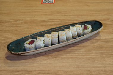 Bir tabak suşi, mavi tabak ve beyaz tabak. Suşi arka arkaya ve yeşil ve kırmızı bir dizaynı var.