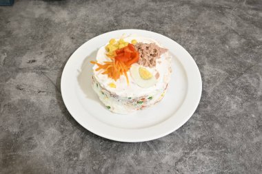 Üzerinde pasta olan beyaz bir tabak. Pasta sebzelerden yapılmıştır ve çeşitli renklere sahiptir.