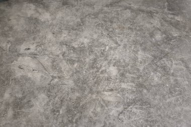 Üzerinde birkaç çizik ve çizik olan gri beton bir zemin. Zemin çok sade ve sade.