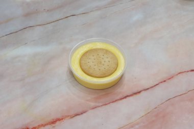 Üstünde kurabiye olan küçük bir kutu sarı krema. Hoşgörü ve rahatlık kavramı, kremalı tatlı ve çıtır kurabiyenin birleşimi tatmin edici ve lezzetli bir ziyafet yaratır.