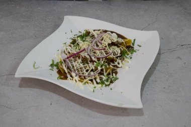 Bir tabak yemek, beyaz tabak ve kahverengi sos. Tabak gri bir yüzeyde.