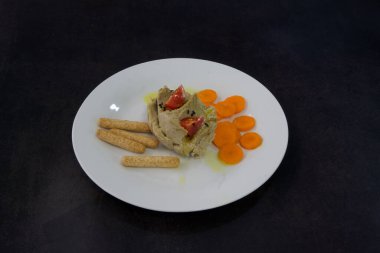 Sebzeli ve krakerli bir tabak yemek. Tabak beyaz, yemek kahverengi.