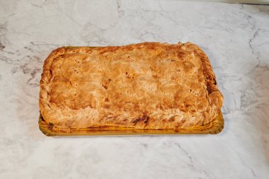 Bir parça yiyecek mermer tezgahın üzerinde duruyor. Bu bir hamur işi ve kahverengi renkli.