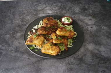 Lahana salatalı bir tabak kızarmış tavuk. Tavuk parçalara ayrılır ve siyah bir tabakta servis edilir.