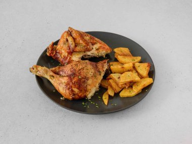 Bir tabak tavuk ve patates. Tavuk ikiye bölünür ve patatesler küp olur.