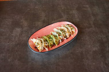 Kırmızı tabakla bir tabak hamur köftesi. Tabakta dokuz tane köfte var.