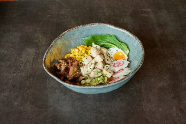 Et, sebze ve yumurtalı bir kase yemek. Kase mavi ve üzerinde yeşil bir yaprak var.