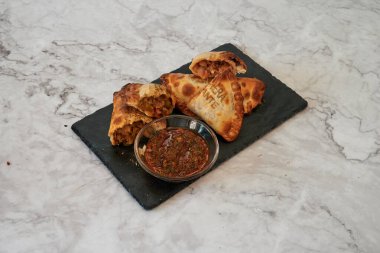 Yanında bir kase sos olan bir tabak yemek. Yemek bir çeşit hamur işi.