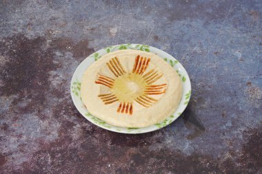 Yeşil yapraklı bir tabak humus. Tabak masanın üstünde.