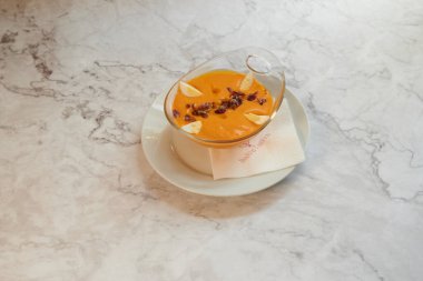 Üstünde peçete olan bir kase çorba. Peçete beyaz ve kırmızı kenarı var.