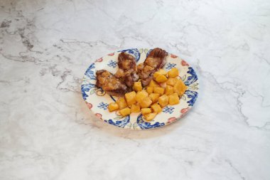 Mermer tezgahta bir tabak et ve meyve. Et şeritler halinde kesilir ve meyve küp şeklinde kesilir.