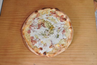 Üstünde peynir ve jambon olan bir pizza. Peynir yayılmış, jambon ortada.