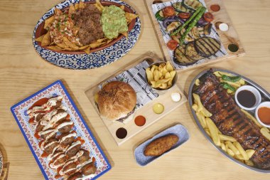 İçinde bir sandviç, bir tabak patates kızartması ve bir tabak et olan bir masa.