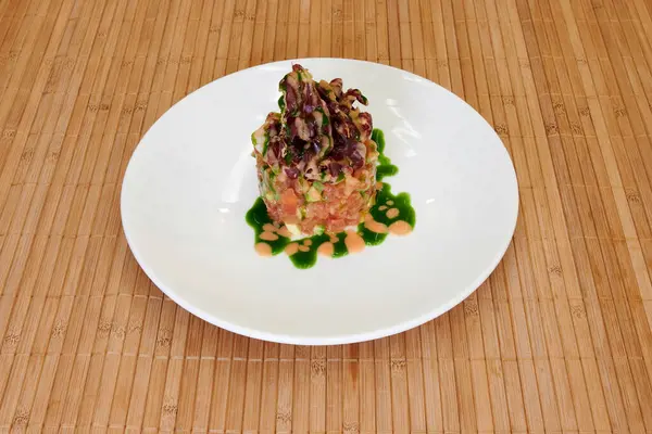 Üstünde yeşil sos olan bir tabak yemek. Tabak beyaz, yemek kahverengi.