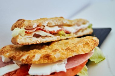 Jambonlu ve marullu sandviç ikiye bölünür. Üst yarısı yine ikiye bölünmüş.