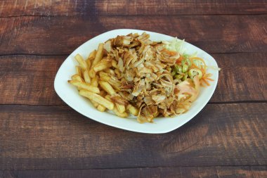 Bir tabak et ve yanında da patates kızartması. Et küçük parçalara ayrılır ve yanında sebze ile servis edilir.