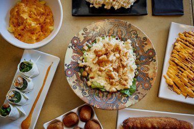 Bir tabak makarna da dahil olmak üzere bir sürü farklı yemek çeşidi olan bir masa. Masada tabaklar ve kaseler de var.