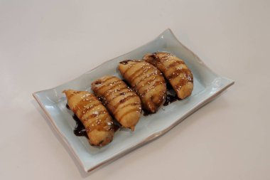 Çikolata soslu dört tabak çörek. Tabak beyaz bir masada.