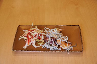 Bir tabak et ve sebzeyle birlikte bir tabak yemek. Tabak kahverengi ve üzerinde bir desen var.