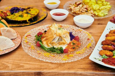 Çeşitli yiyeceklerle dolu bir masa, üzerinde beyaz tabak olan bir tabak yemek de dahil.