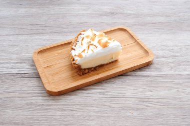 Krem şantili bir dilim turta. Tahta bir tepside. Turta ikiye bölündü.