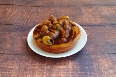 Üzerinde mantar ve zeytin olan bir tabak yemek. Tabak beyaz, yemek kahverengi.