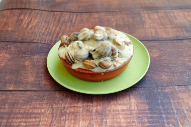 Üzerinde mantarlı turta olan yeşil bir tabak. Turta kremalı sosla kaplı. Tabak ahşap bir masada duruyor.