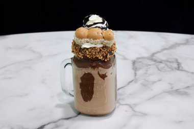 Çikolatalı dondurma ve fındık dolu bir bardak. Cam mermer tezgahın üzerinde.