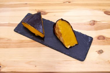 Bir parça yiyecek ikiye ayrılır ve siyah bir tabağa yerleştirilir. Tabak ahşap bir masanın üzerinde.