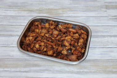 Bir tepsi pastırma ve ekmek kırıntısı. Pastırma küçük parçalara bölünmüş. Tepsi gümüş.