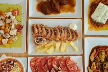 Bir tabak et ve patates de dahil olmak üzere bir sürü farklı yemek tabağı olan bir masa. Sebze tabakları ve diğer yemekler de var.