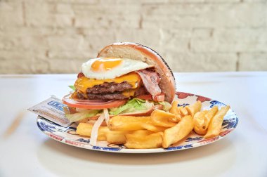 Pastırmalı ve peynirli hamburger. Hamburgerin üzerinde kızarmış yumurta da var.