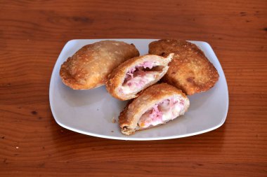 Üzerinde dört hamur işi olan bir tabak. Hamur işlerinden biri açık. Diğer üçü kapalı.