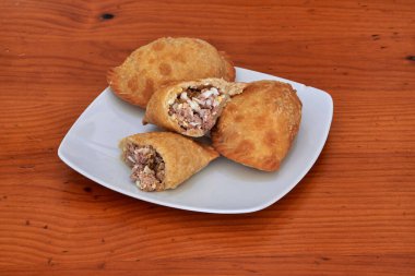 Beyaz tabakta üç sosisli var. Sosislilerden biri kısmen yenmiş.