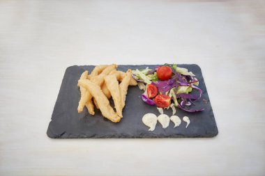 Bir tabak yemek, salata ve biraz kızarmış yiyecek. Salatada domates var.