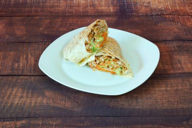 Üstünde burrito olan bir tabak. Burrito ikiye bölündü. Tabak beyaz.