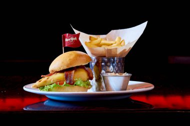 Pastırma ve marullu leziz bir burger, yanında da kızarmış patates. Tabağın üzerine kırmızı bir bayrak konur, biraz renk katar.