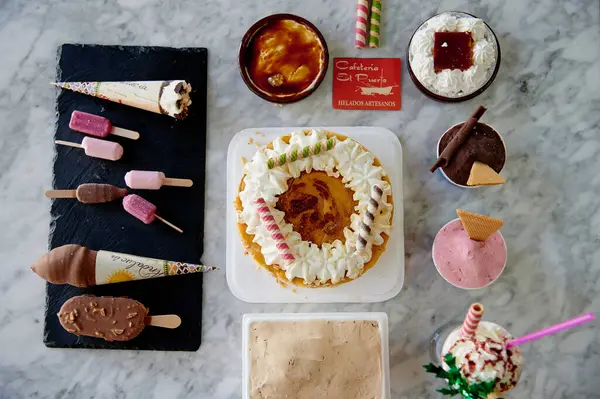 İçinde pasta, dondurma ve diğer ikramlardan oluşan çeşitli tatlılar olan bir masa. Masanın üzerinde 