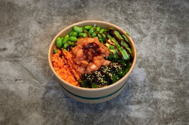 Sebze ve et karışımı bir kase yiyecek. Kâse kağıttan yapılır ve gri bir yüzeye yerleştirilir.