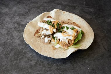 Üzerine sarılmış bir tabak yemek. Paket marul ve peynirle dolu. Tabak tezgahın üstünde.