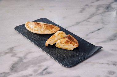 Bir pasta ikiye bölünür ve siyah bir tabağa yerleştirilir. Tabak mermer tezgahın üzerinde.