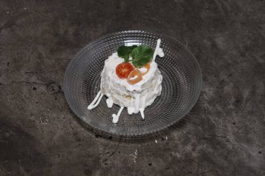 Beyaz soslu ve üstünde domates dilimi olan lezzetli bir tatlı. Sos tatlı üzerine serpilmiş, biraz tatlılık ve keskinlik katıyor. Domates dilimi renk katıyor.