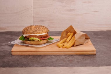 Tahtada sandviç ve patates kızartması. Patatesler kese kağıdında.