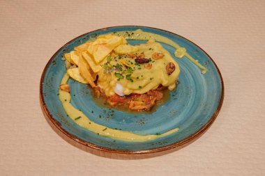 Üzerinde sarı sos ve bir parça yiyecek olan mavi bir tabak. Tabak beyaz bir masaya konur.