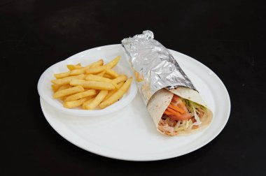 Bir tabak patates kızartması ve bir paket yiyecek. Paket folyoya sarılmış.