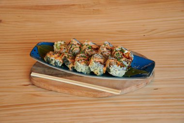 Mavi tabak ve çubuklu bir tabak suşi. Suşi tahtanın üzerinde.