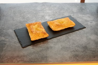 Siyah tabakta iki hamur işi. Biri solda ve diğeri sağda.