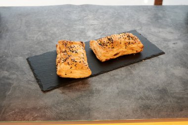 Siyah tabakta iki hamur işi. Biri solda ve diğeri sağda.